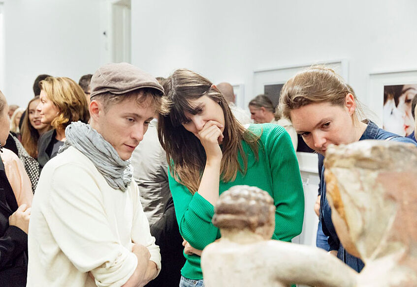zwei Frauen und ein Mann betrachten eine Skulptur